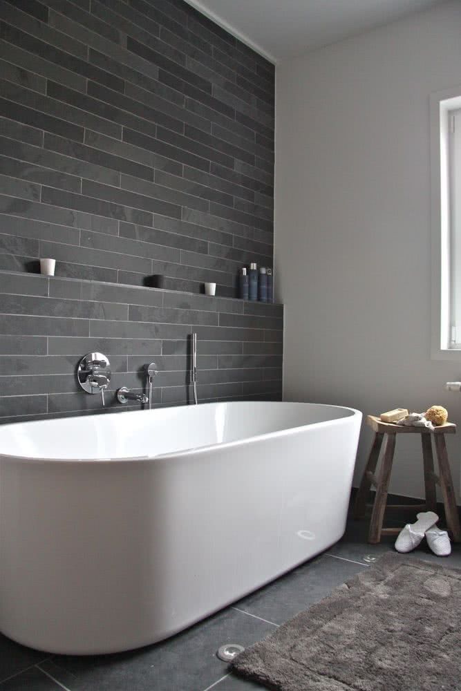 pared gris con repisa de obra, bañera curva