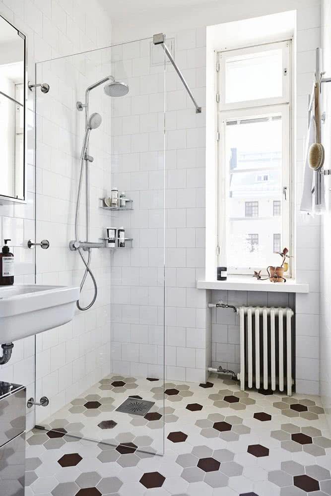 ducha con mampara fija de vidrio, suelo con azulejos hexagonales, paredes blancas