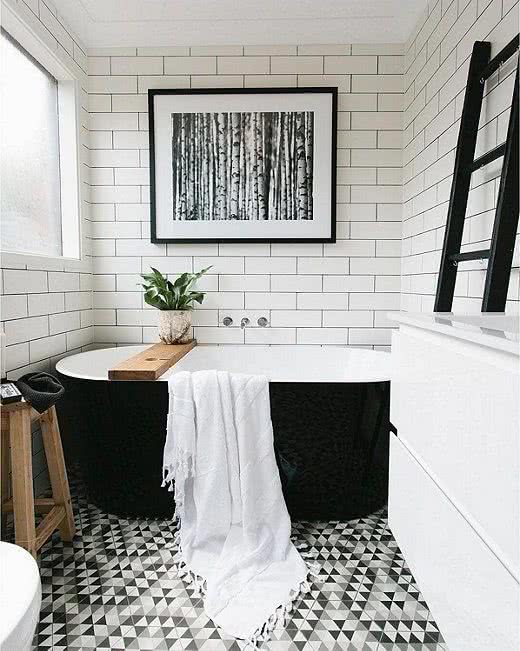paredes blancas, bañera negra y suelos geométrico en blanco, gris y negro