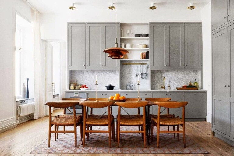 cocina comedor con armarios grises, azulejos que imitan etas de piedra, comedor y suelos en madera