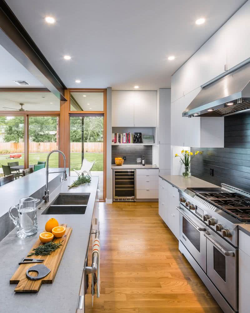 cocina de pared e isla en paralelo, en tonos de gris y blanco, suelo en madera