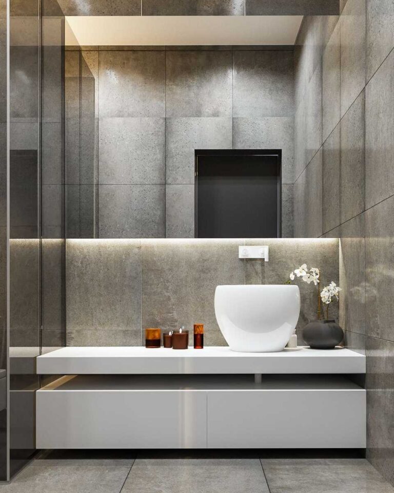 baño moderno con cerámicos grises, espejo longitudinal sobre encimera con mueble bajo blanco