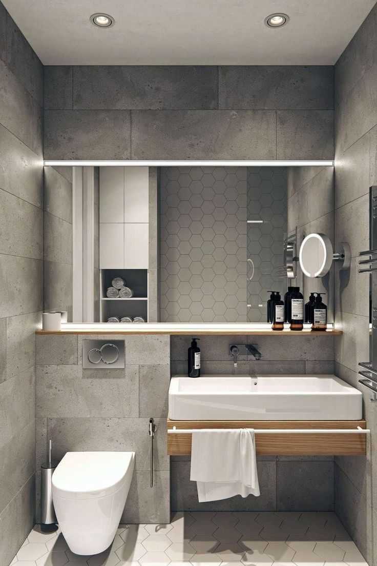 paredes con azulejos rectangulares grises que simulan piedra, espejo horizontal, lavabo rectangular con toallero
